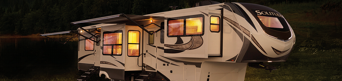 A Forest River Cross Roads Sunset RV with some extendable features lit up at night
